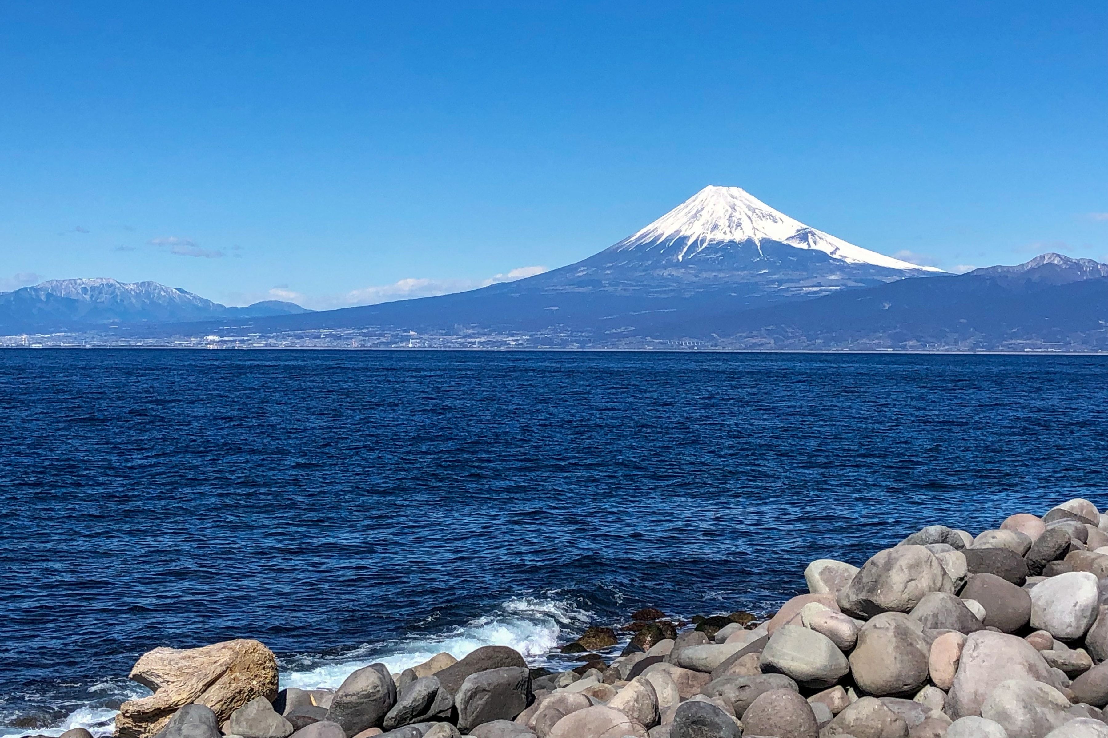 海の向こうに見える、雪をかぶった富士山